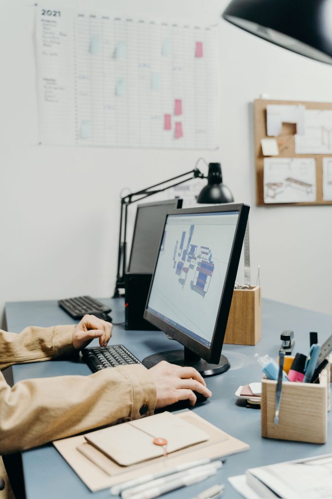 A person working at a desk with a computer monitor in an organized office setting.